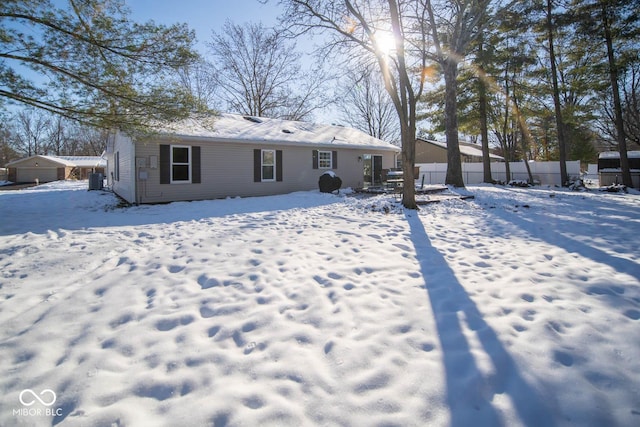 snow covered rear of property featuring central AC