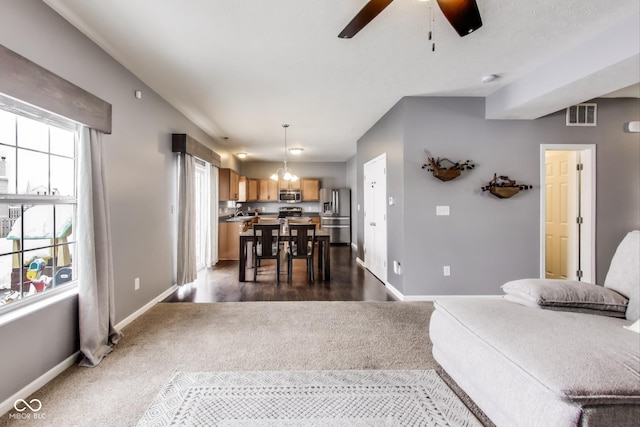 carpeted living room featuring ceiling fan with notable chandelier