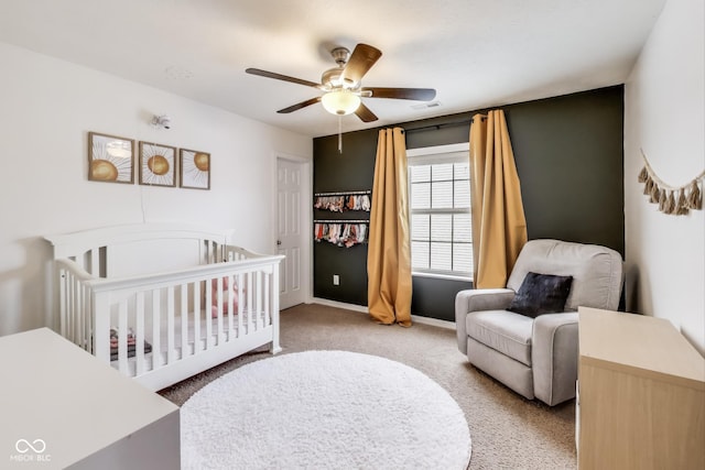 carpeted bedroom featuring ceiling fan and a nursery area