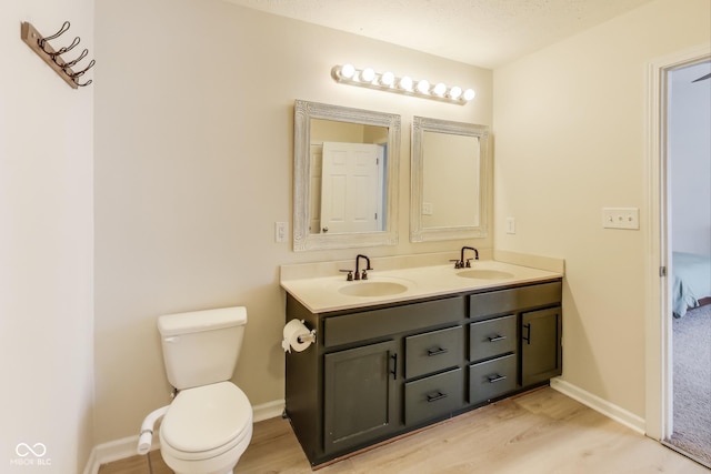 bathroom with toilet, hardwood / wood-style flooring, a textured ceiling, and vanity