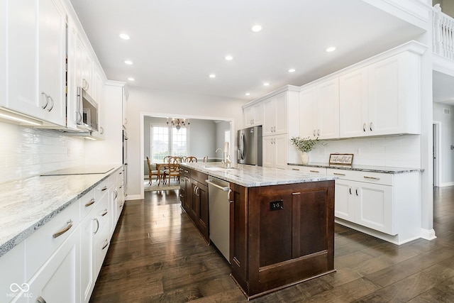 kitchen with stainless steel appliances, light stone counters, tasteful backsplash, a kitchen island with sink, and dark wood-type flooring