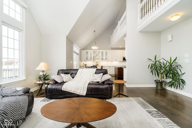 living room featuring a healthy amount of sunlight, dark wood-type flooring, and high vaulted ceiling