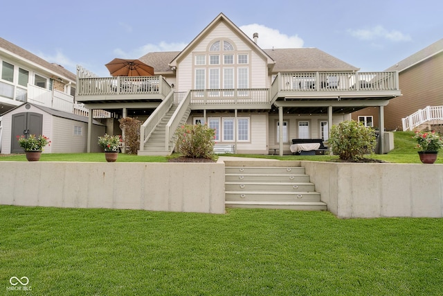 rear view of property with a yard, a deck, and a storage shed