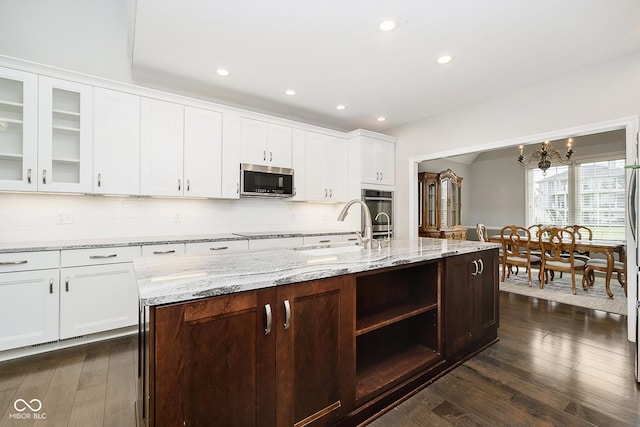 kitchen with an island with sink, dark wood-type flooring, white cabinets, and sink