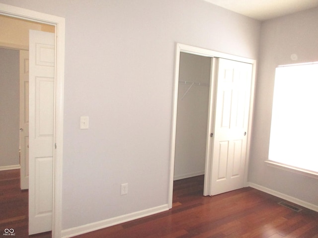 unfurnished bedroom featuring dark wood-type flooring and a closet