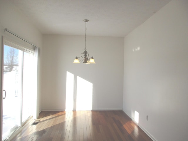 unfurnished dining area featuring a chandelier and dark hardwood / wood-style flooring