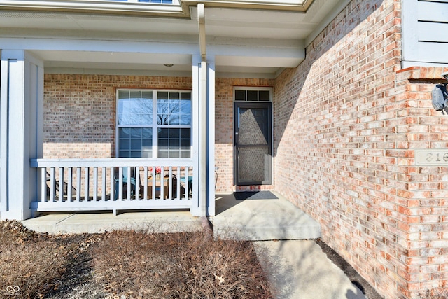 property entrance featuring a porch and brick siding