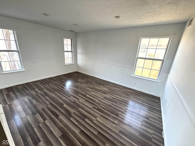 spare room with a textured ceiling and dark hardwood / wood-style flooring