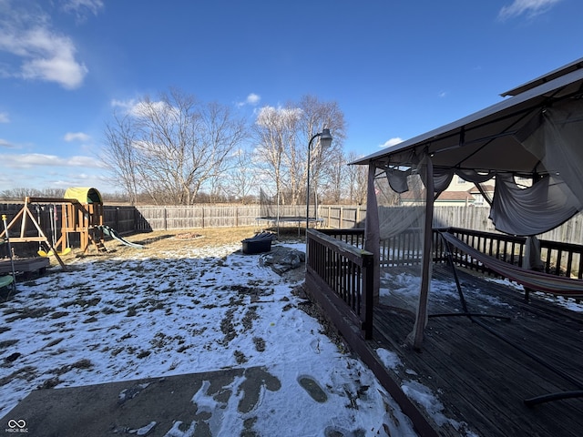 snowy yard featuring a playground and a trampoline