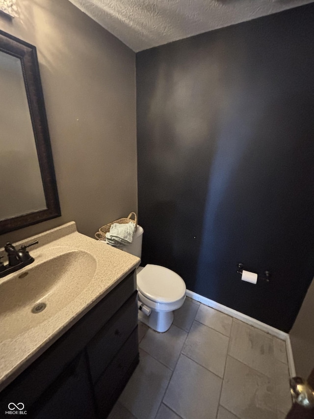 bathroom with a textured ceiling, toilet, tile patterned flooring, and vanity