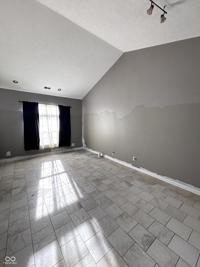 spare room with vaulted ceiling and a textured ceiling