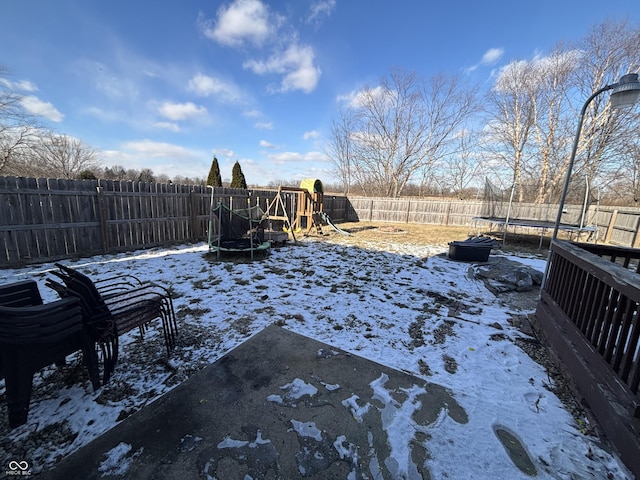 yard covered in snow with a playground and a trampoline