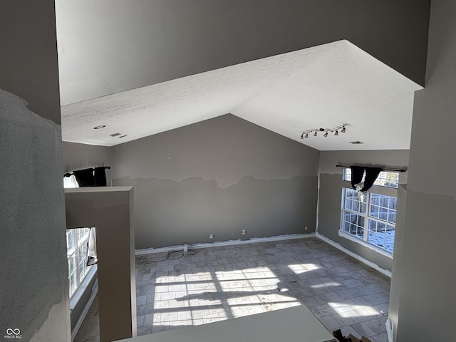 interior space featuring vaulted ceiling, a textured ceiling, and rail lighting