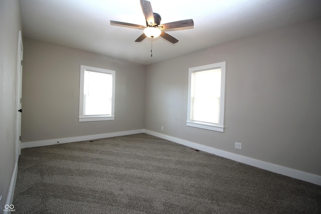 empty room featuring ceiling fan and dark colored carpet