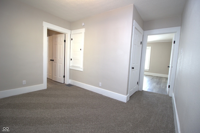 interior space featuring a textured ceiling and dark carpet