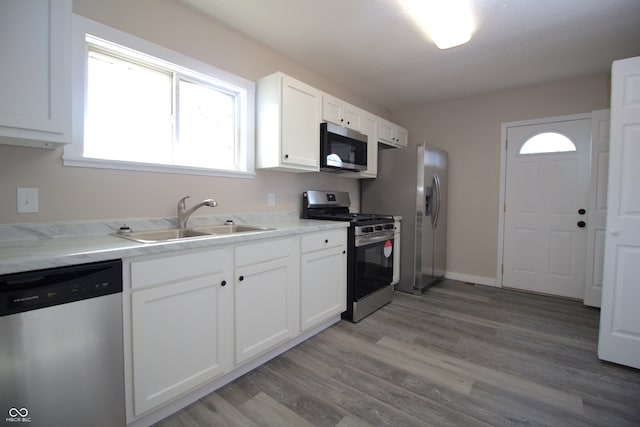 kitchen featuring light wood-type flooring, appliances with stainless steel finishes, sink, and white cabinets