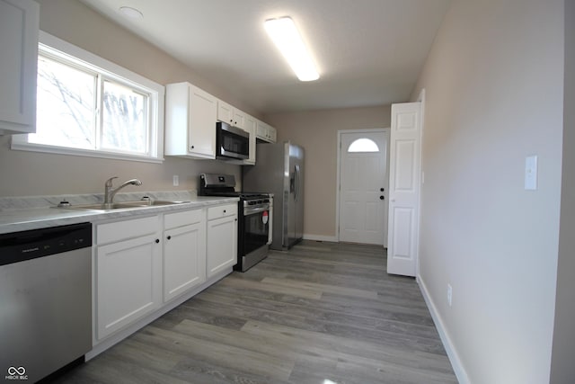 kitchen featuring stainless steel appliances, white cabinetry, sink, and light hardwood / wood-style floors