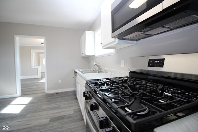 kitchen featuring white cabinetry, appliances with stainless steel finishes, light hardwood / wood-style floors, and sink