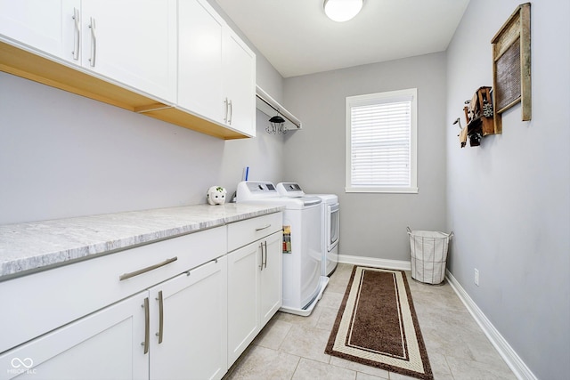 clothes washing area with cabinets, washer and clothes dryer, and light tile patterned floors