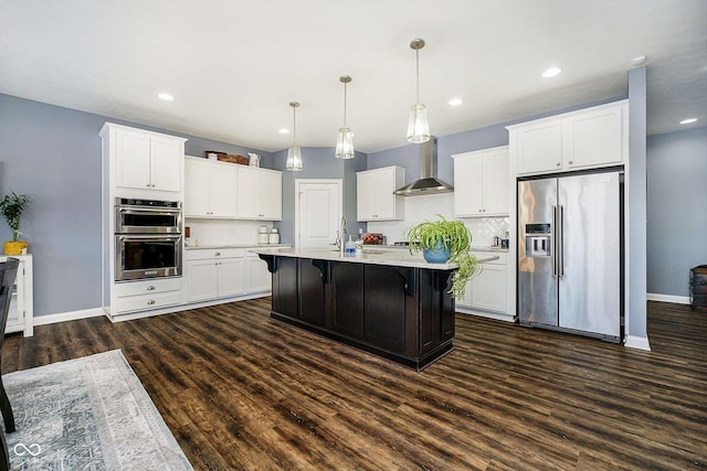 kitchen with white cabinetry, decorative light fixtures, wall chimney exhaust hood, and appliances with stainless steel finishes