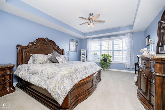 carpeted bedroom with ceiling fan and a raised ceiling