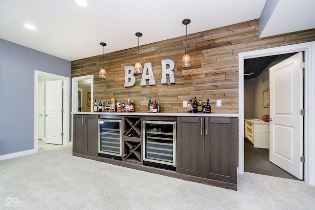 bar with hanging light fixtures, carpet, wine cooler, and wood walls