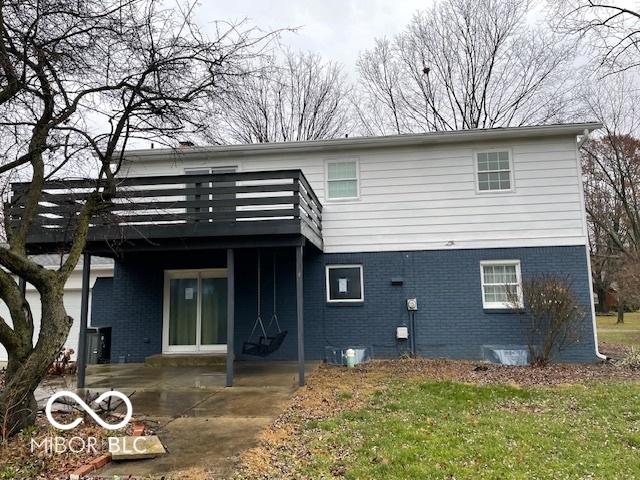 rear view of property with a wooden deck, a patio area, and a yard