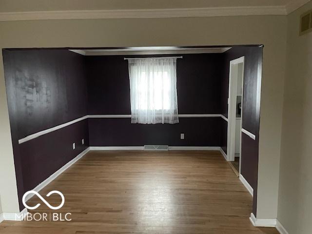 empty room with wood-type flooring and ornamental molding