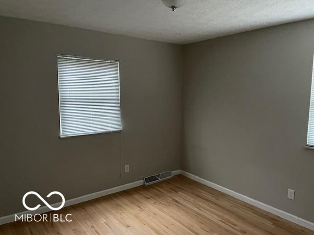 spare room with a textured ceiling and light hardwood / wood-style flooring