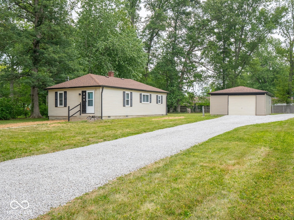 view of front of property with a front yard, a garage, and an outbuilding