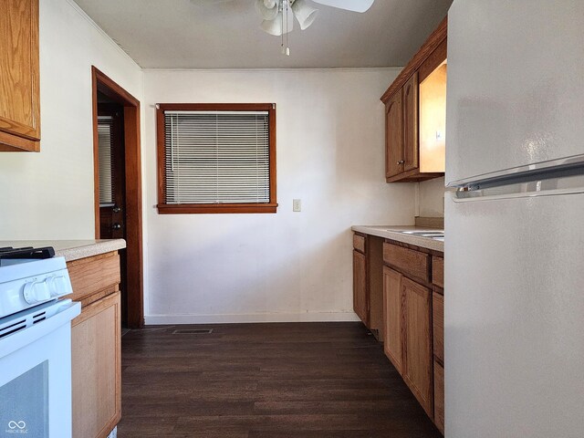 kitchen featuring baseboards, light countertops, dark wood-style floors, white appliances, and a ceiling fan