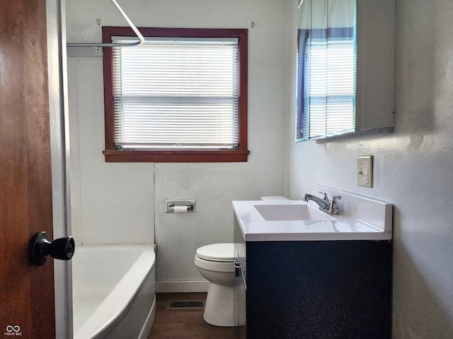 bathroom featuring visible vents, toilet, a tub to relax in, wood finished floors, and vanity