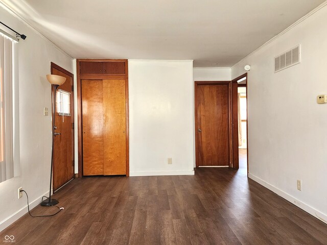 unfurnished bedroom with visible vents, baseboards, ornamental molding, and dark wood-style flooring