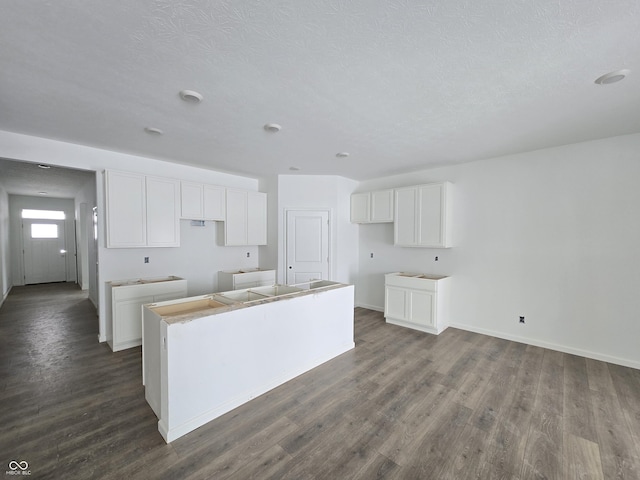 kitchen featuring white cabinetry, dark hardwood / wood-style flooring, a kitchen island, and a textured ceiling