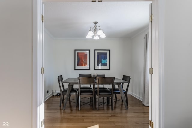 dining area with hardwood / wood-style flooring, crown molding, and a notable chandelier