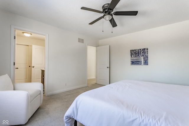 bedroom with ceiling fan, light colored carpet, and connected bathroom