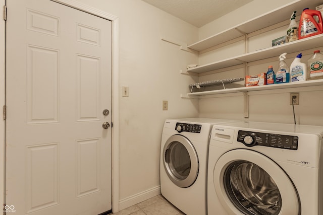 clothes washing area featuring a textured ceiling, light tile patterned floors, and washer and clothes dryer