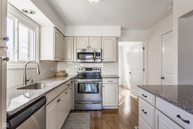 kitchen featuring backsplash, appliances with stainless steel finishes, sink, and stone counters