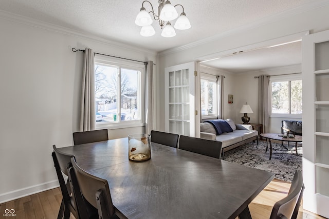 dining area with hardwood / wood-style flooring, a textured ceiling, crown molding, and a chandelier