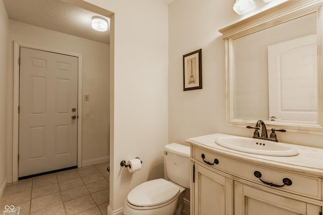 bathroom featuring a textured ceiling, toilet, tile patterned floors, and vanity