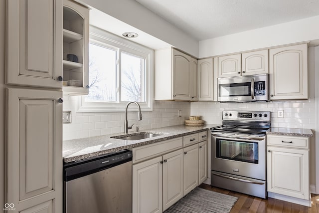 kitchen featuring tasteful backsplash, appliances with stainless steel finishes, sink, and light stone counters