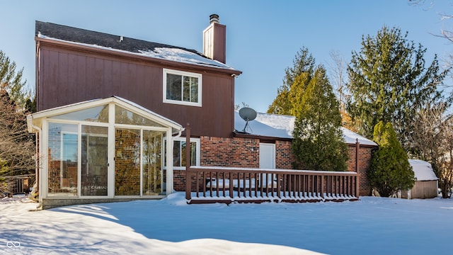 snow covered property featuring a wooden deck and a sunroom