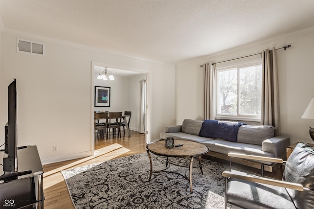 living room featuring a chandelier, crown molding, and light hardwood / wood-style floors