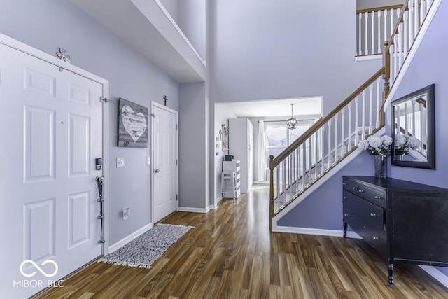 foyer with a high ceiling, an inviting chandelier, and dark hardwood / wood-style flooring