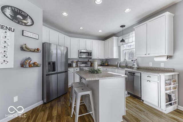 kitchen with stainless steel appliances, a center island, hanging light fixtures, and white cabinets