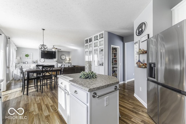 kitchen with white cabinets, a kitchen island, stainless steel fridge, and dark hardwood / wood-style flooring