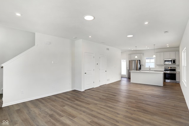 kitchen with a center island, white cabinetry, hanging light fixtures, appliances with stainless steel finishes, and dark wood-type flooring