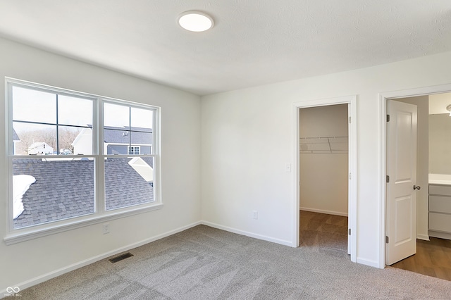 unfurnished bedroom featuring carpet, a walk in closet, and a closet