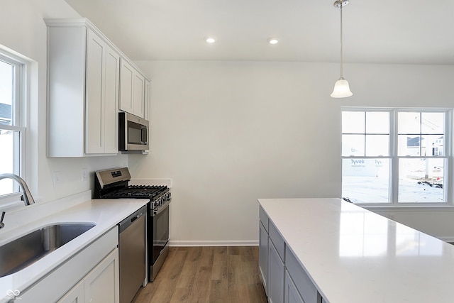 kitchen with decorative light fixtures, sink, white cabinets, and stainless steel appliances