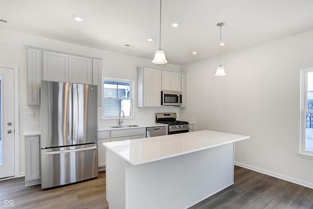 kitchen featuring stainless steel appliances, a center island, decorative light fixtures, and sink